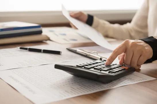Hand using a calculator over financial reports