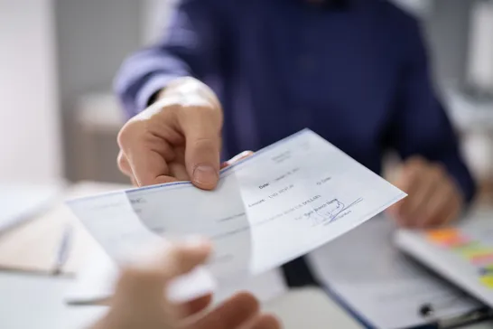Hand passing a paycheck across a desk